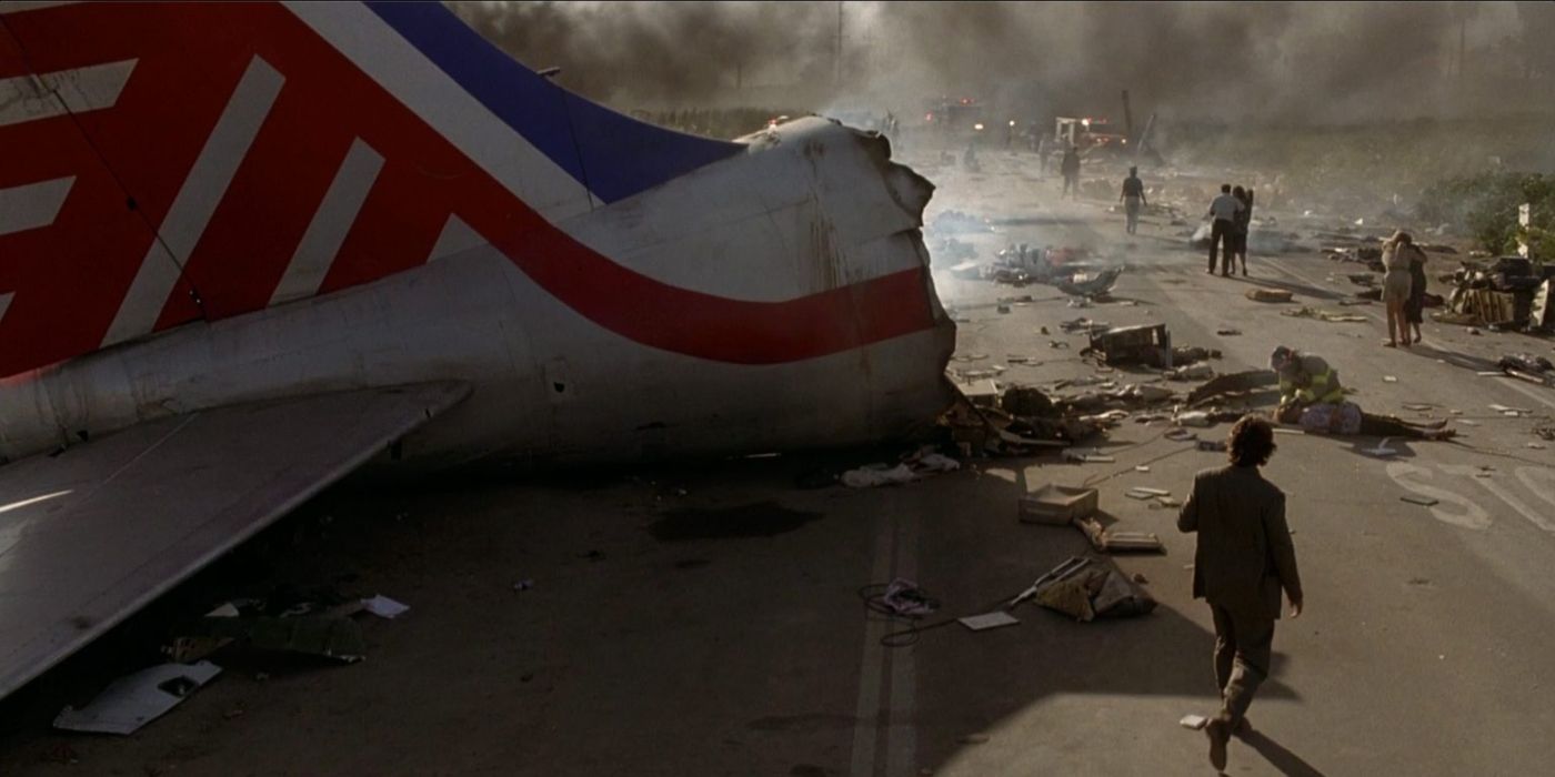 The taile of a large commercial plane sits in the middle of a highway, debris all around