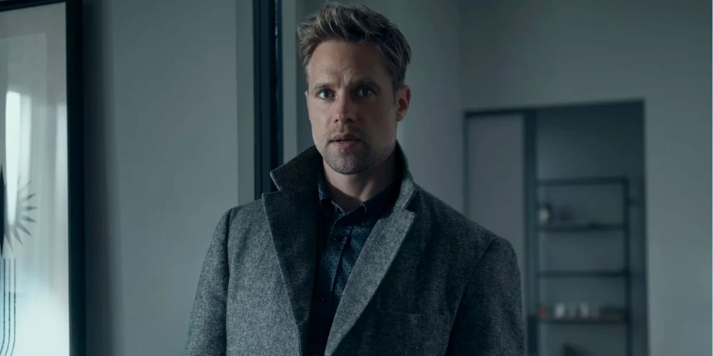 Shaun Sipos as David O'Donnell wearing a large grey coat looking at someone off-screen in Reacher