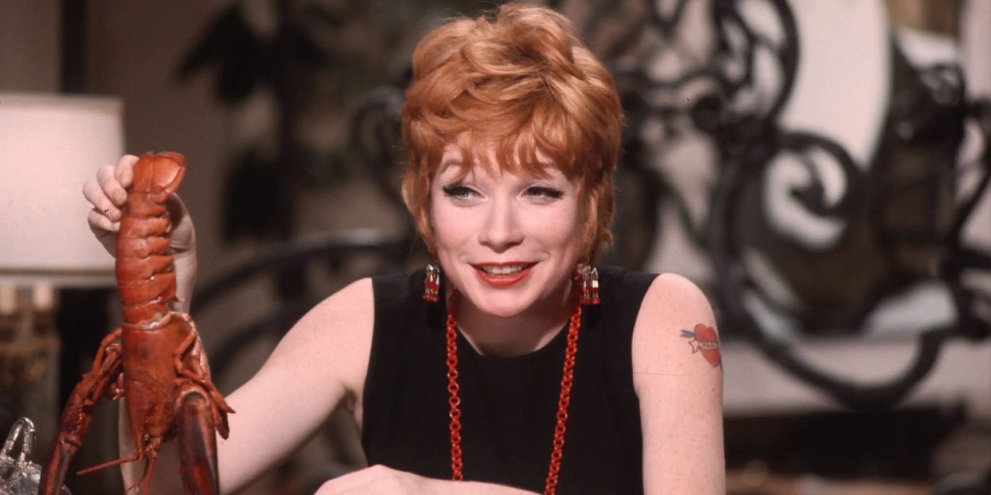 Shirley MacLaine as Charity seated at a table while holding a lobster in her hand in Sweet Charity