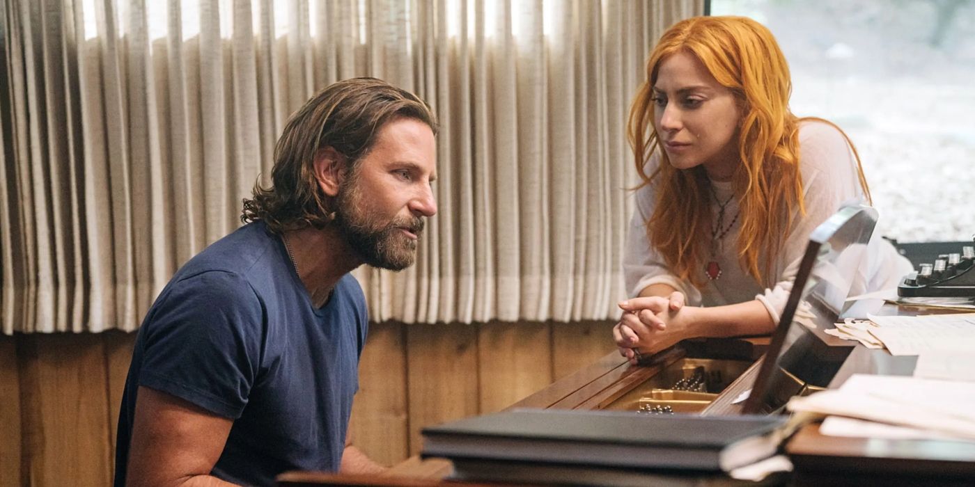Lady Gaga as Ally stands to the side as Bradley Cooper as Jackson plays a song on the piano in A Star is Born