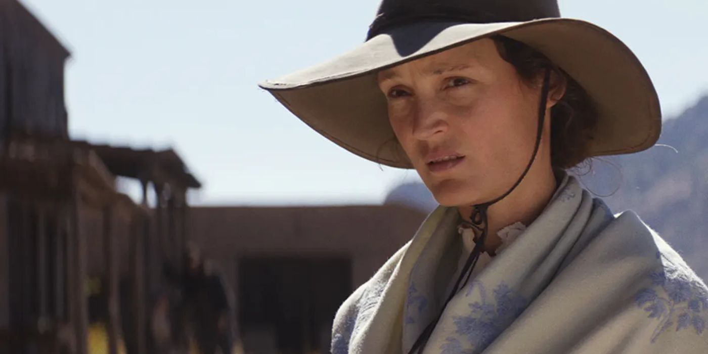 Vicky Krieps as Vivienne Le Coudy wearing a large hat and scarf in the west in The Dead Don't Hurt