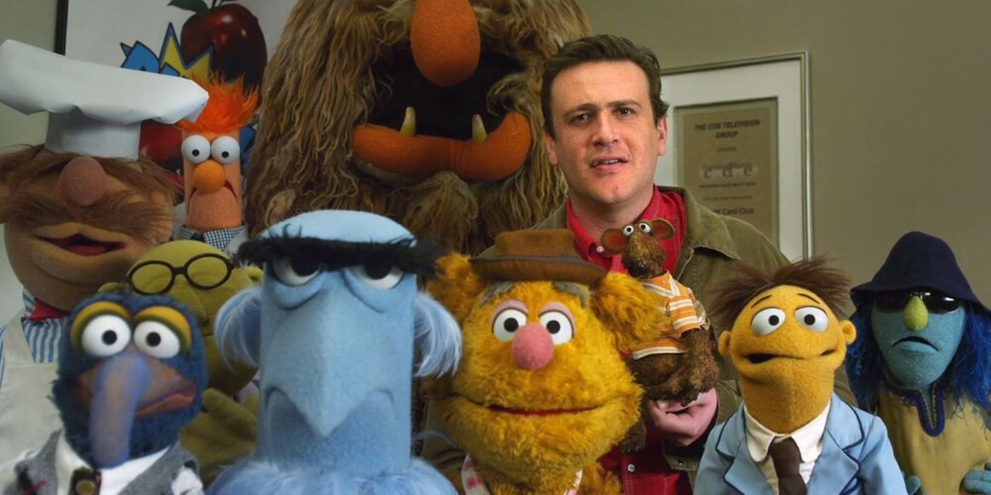 Jason Segel as Gary, standing with a group of Muppets, in The Muppets