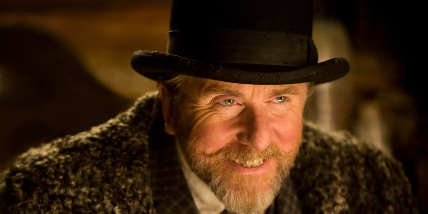 Tim Roth in Tarantino's movie The Hateful Eight as Oswaldo Mobray wearing a top hat and smiling