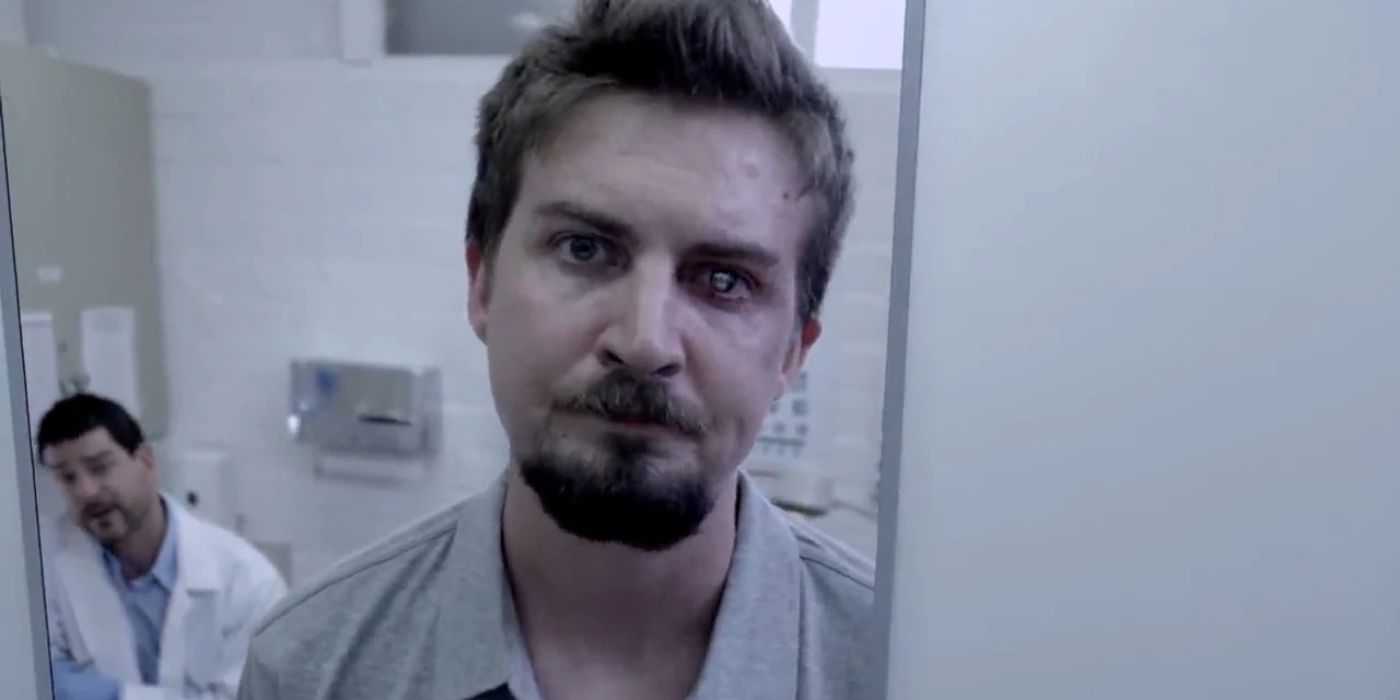 A close-up of a man looking into a mirror in a medical room