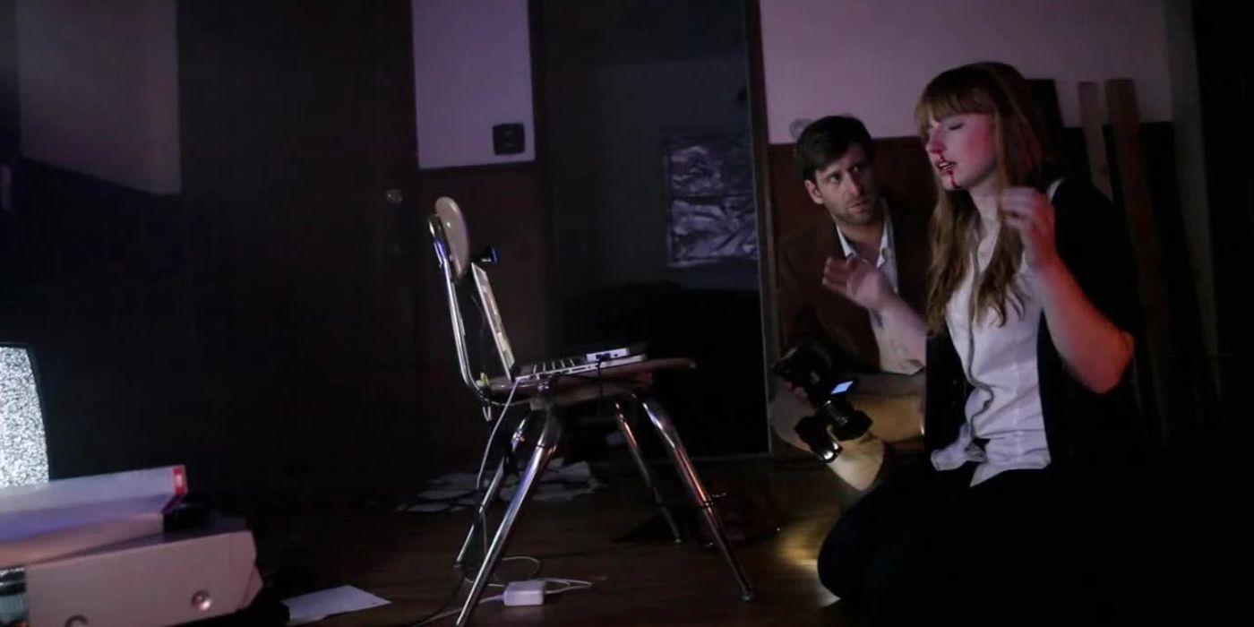 A grainy image of a young couple sitting in a dark room together