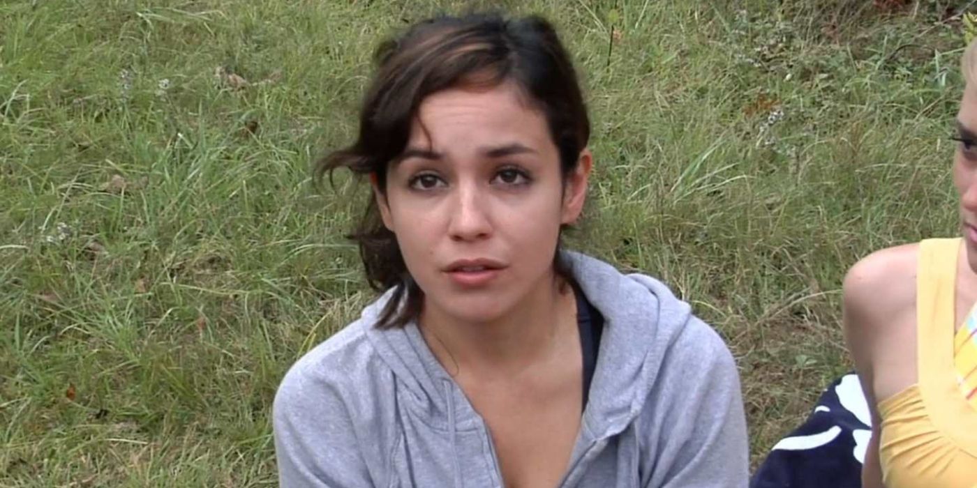 A young woman in a grassy field looks up at the sky