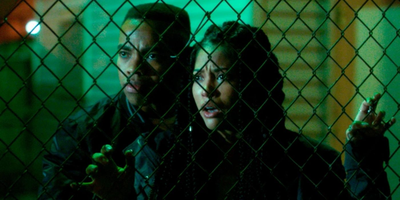 Nya and Isaiah stare through a fence in The First Purge