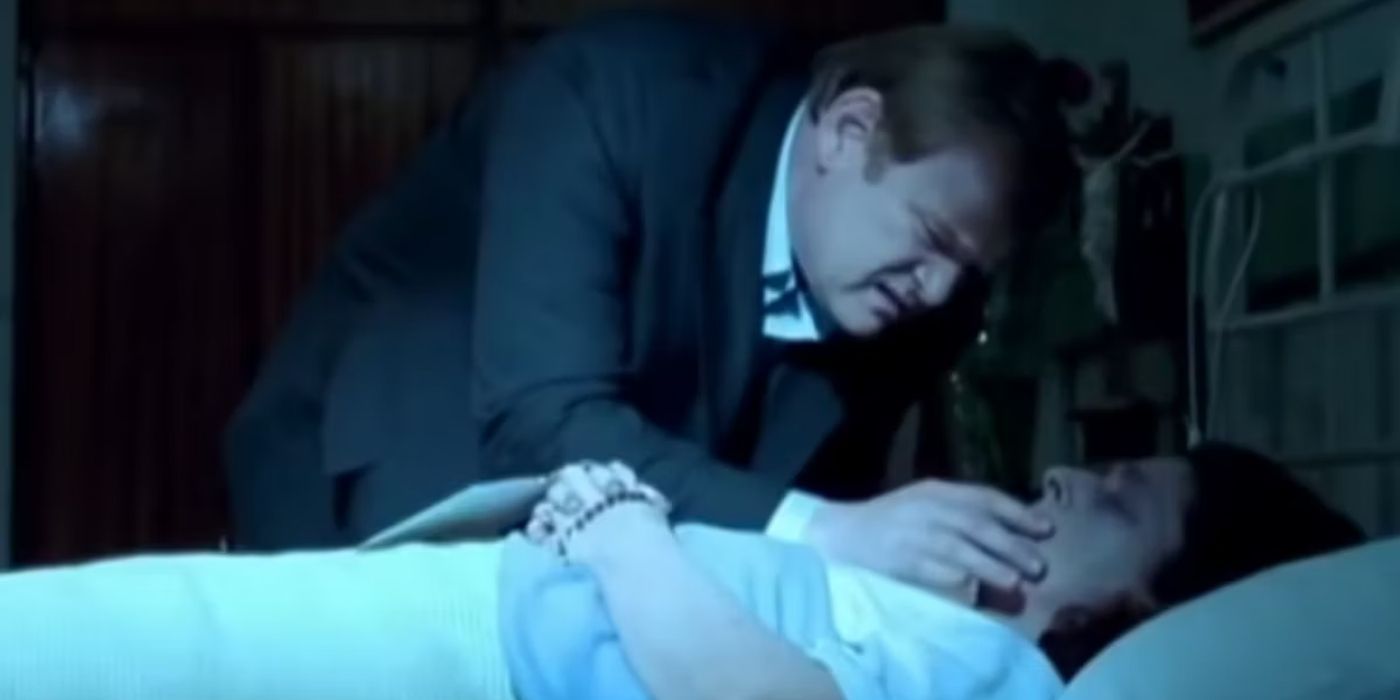 Brendan Gleeson leans over a man in bed in Six Shooter (2004)