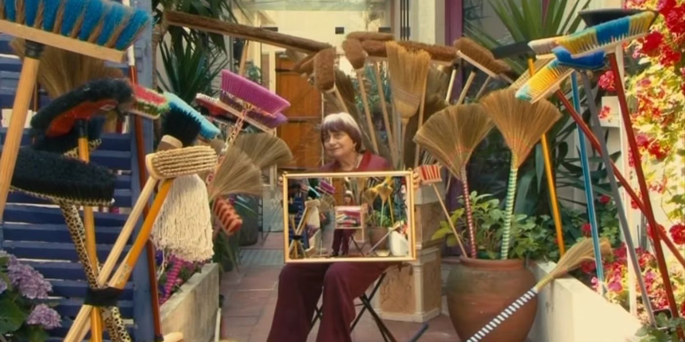 Agnes Varda posing with a bunch of brooms in The Beaches of Agnes