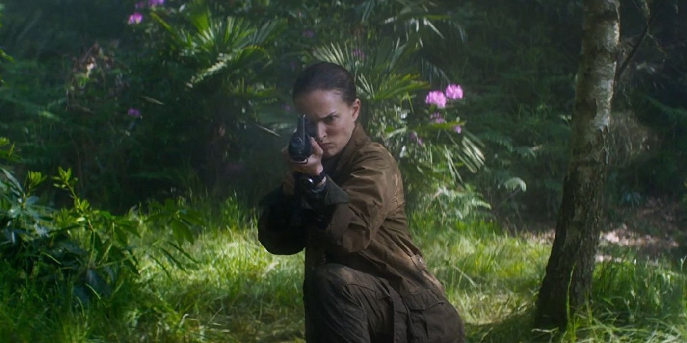 Natalie Portman as Lena, crouched down in a strange forest and firing her gun