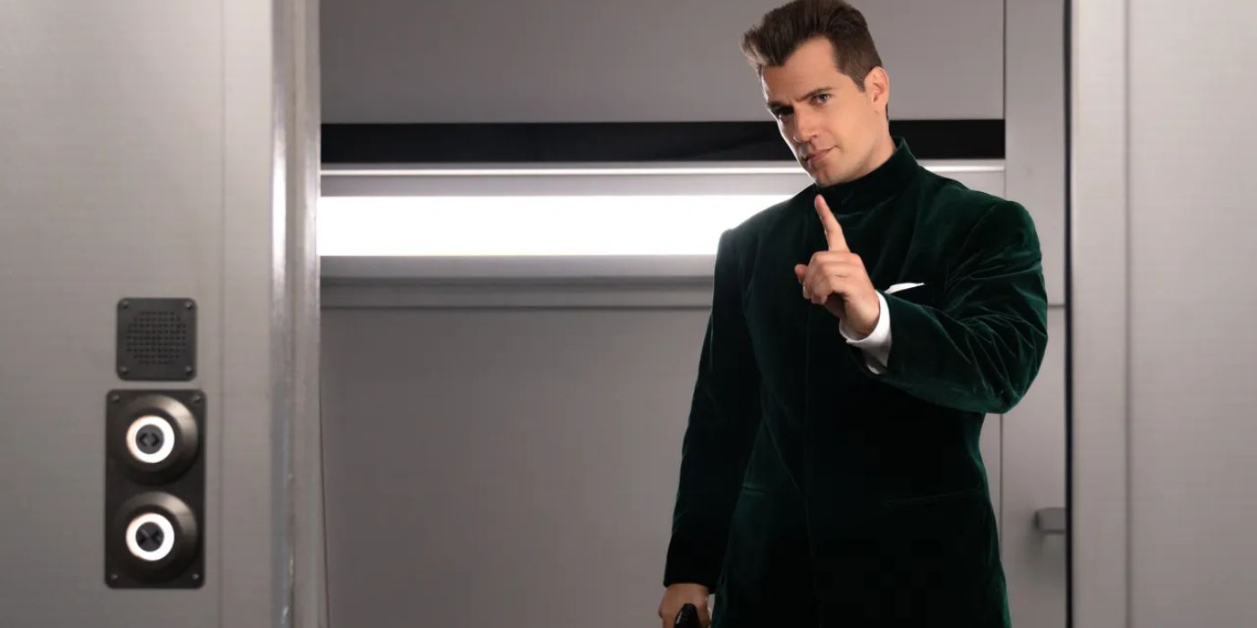 Henry Cavill as Argylle wearing a green suit holding a gun on a train in Argylle