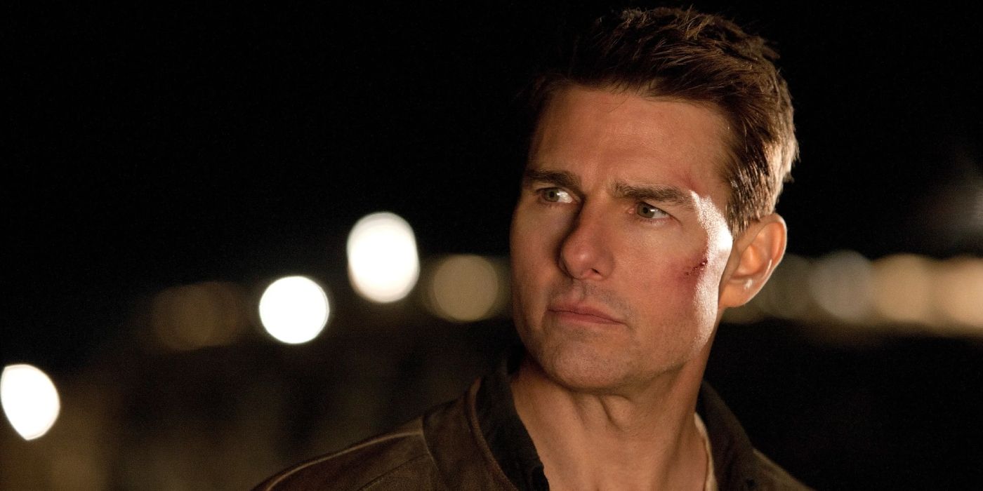 Tom Cruise as Jack Reacher wearing a brown jacket with a small cut on his cheek looking off-scren in Jack Reacher