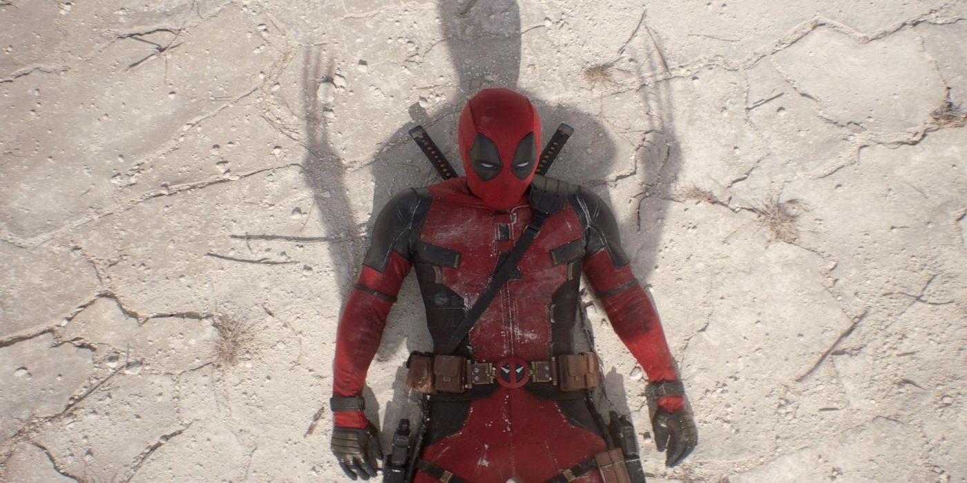 Deadpool laying on the ground in his red suit after a fight with wolverine standing over him in Deadpool 3