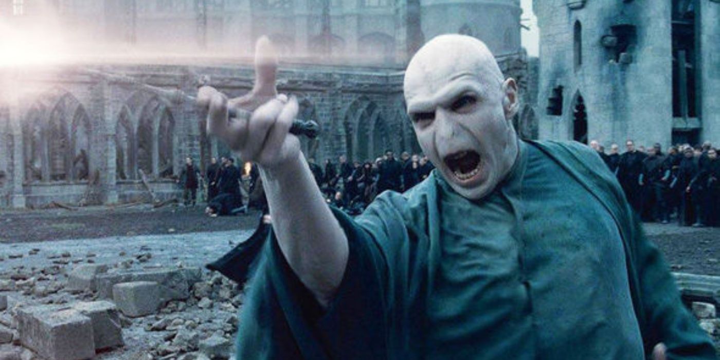 Ralph Fiennes as Voldemort with no nose and no hair standing in the courtyard of Hogwarts using his wand in Harry Potter