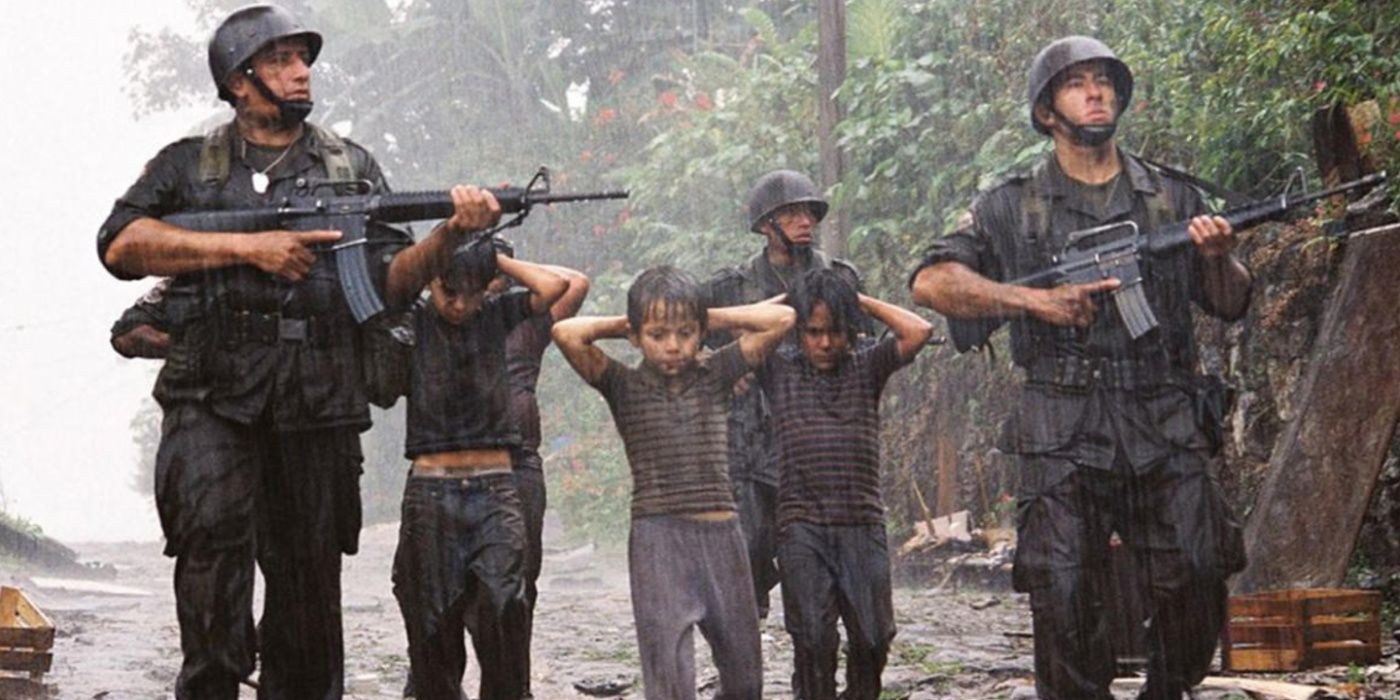 Three young boys hold their hands to their heads as they're escorted by armed soldiers