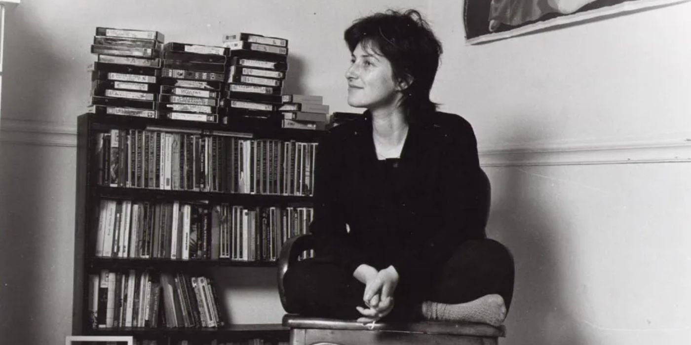 Photo of Chantal Akerman sitting cross-legged on a chair