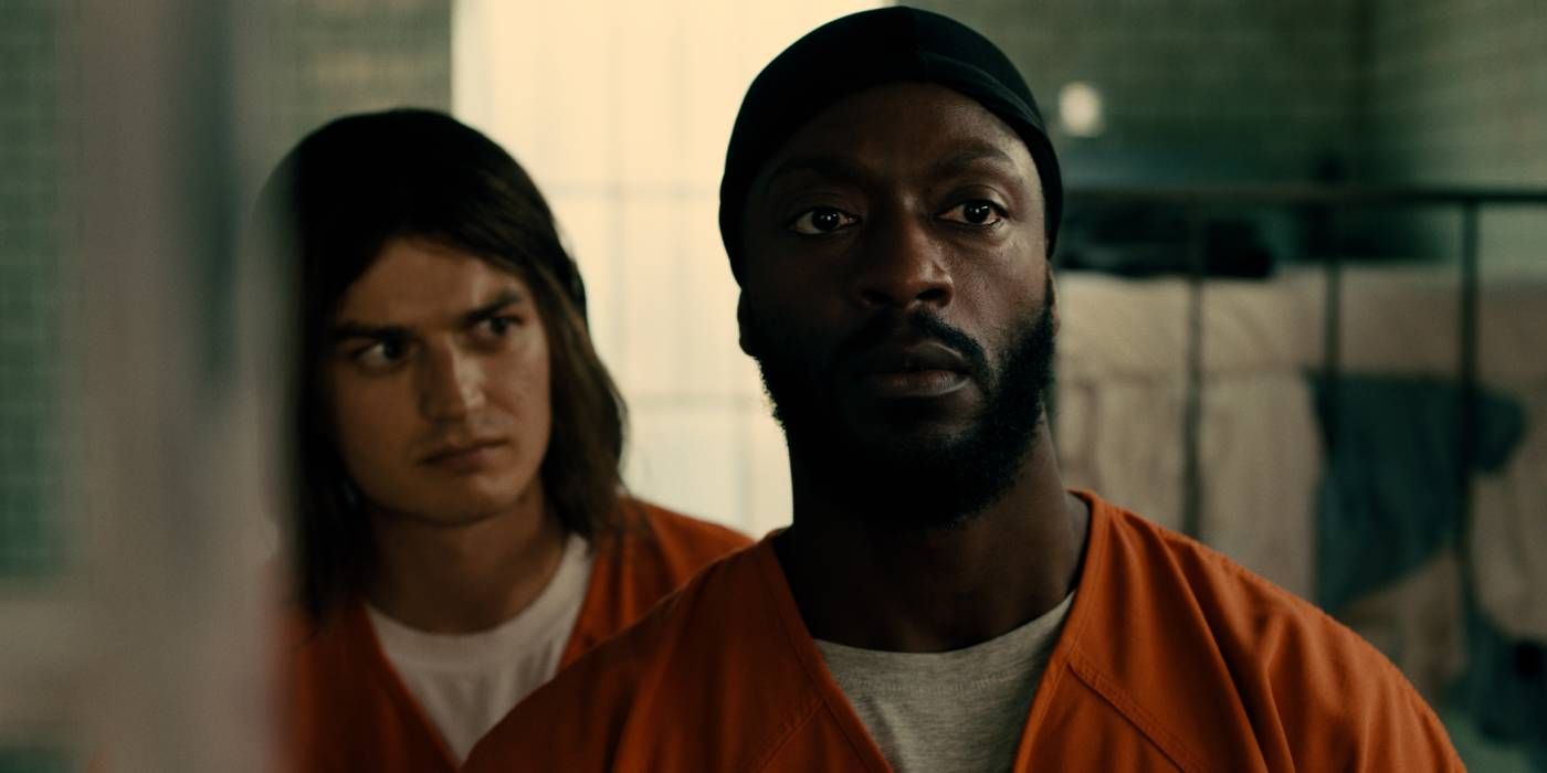 Joe Keery como Barão e Aldis Hodge como Otis vestindo macacões de prisão olhando para fora das câmeras em Marmalade (2024)