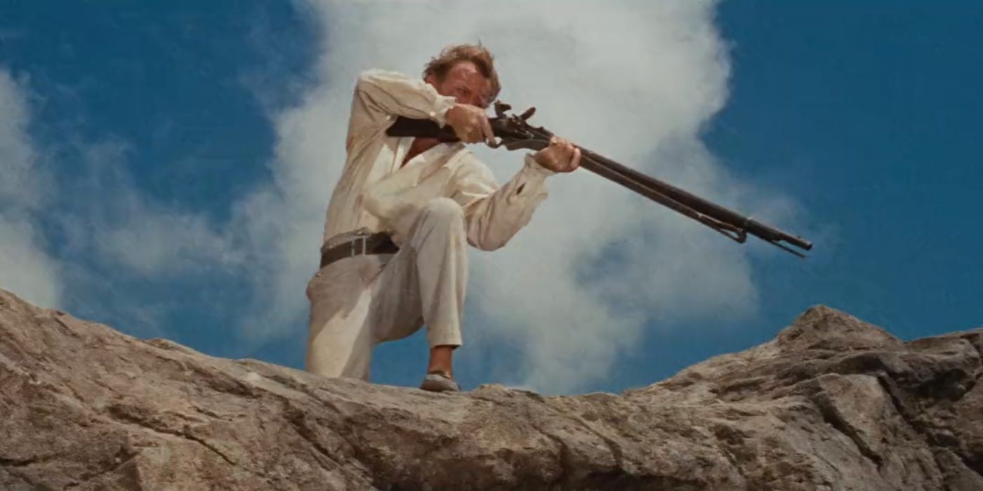 John Mills as Father Robinson pointing a rifle off camera in Swiss Family Robinson (1960)
