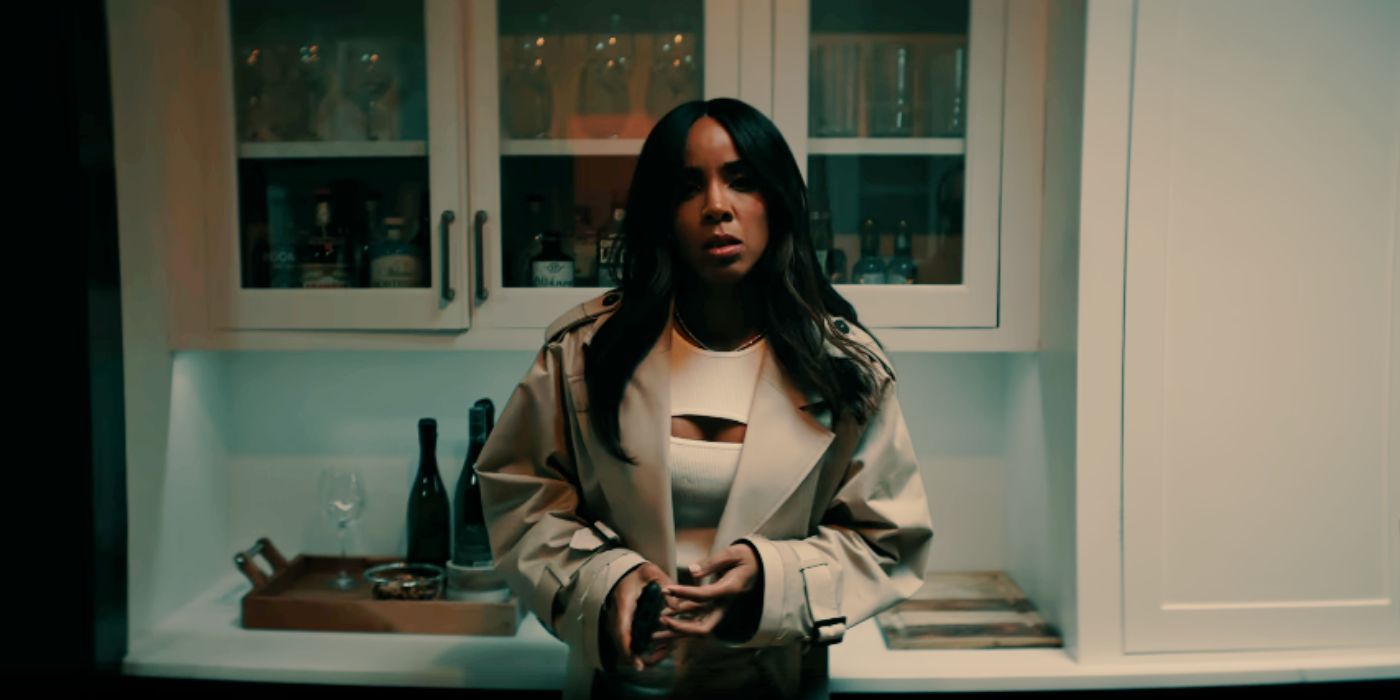 Kelly Rowland as Mea Harper wearing a tan large jacket and white dress standing in a kitchen in Mea Culpa