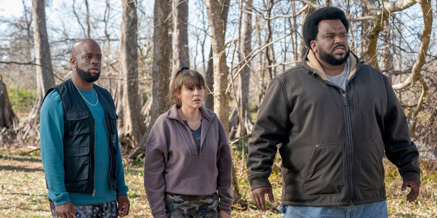 Two men and a woman stand in a forest looking stunned in a scene from Killing It.