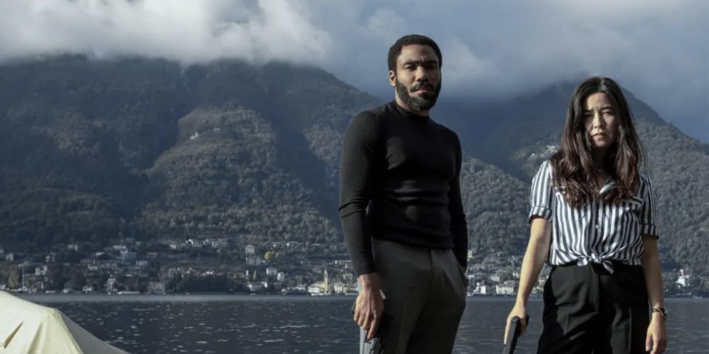 Donald Glover as John and Maya Erskine as Jane in Italy with mountains and cloud behind them in Mr. & Mrs. Smith