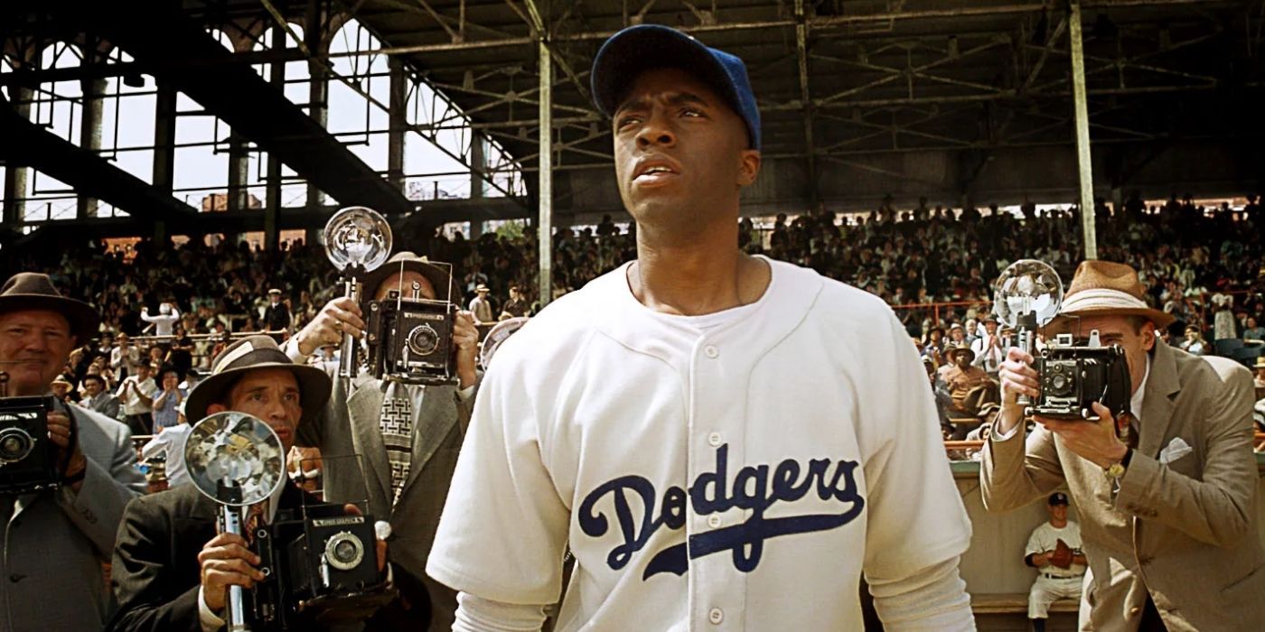 Chadwick Boseman as Jackie Robinson standing in a crowd of press reporters in 42