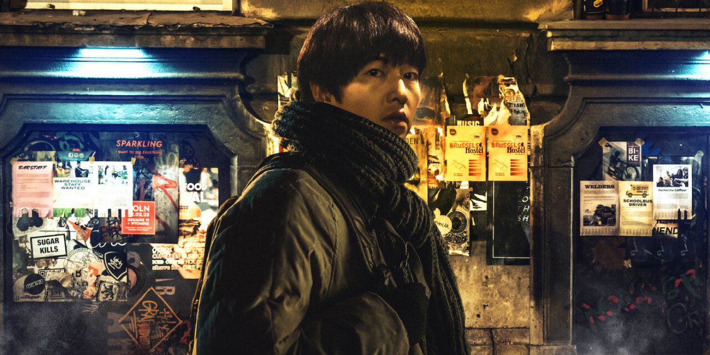 Song Joong-ki as Lo Kiwan wearing a large black jacket and black scarf looking toward the camera in My Name Is Loh Kiwan