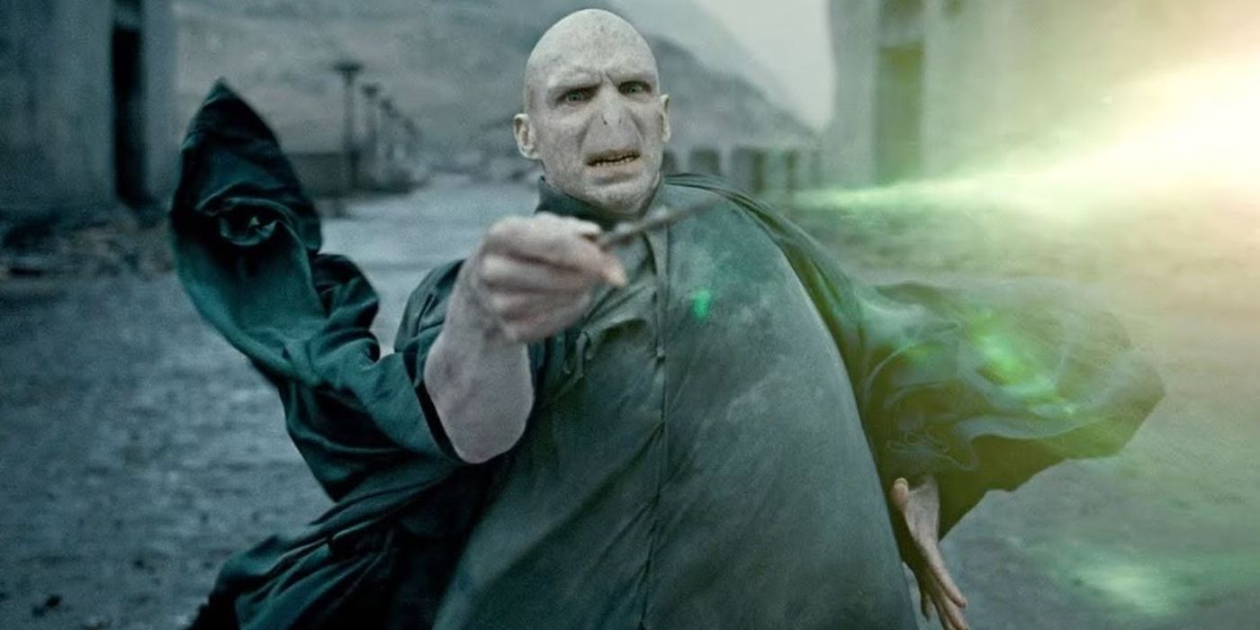 Ralph Fiennes as Voldemort with no nose and no hair standing in the courtyard of Hogwarts using his wand in Harry Potter