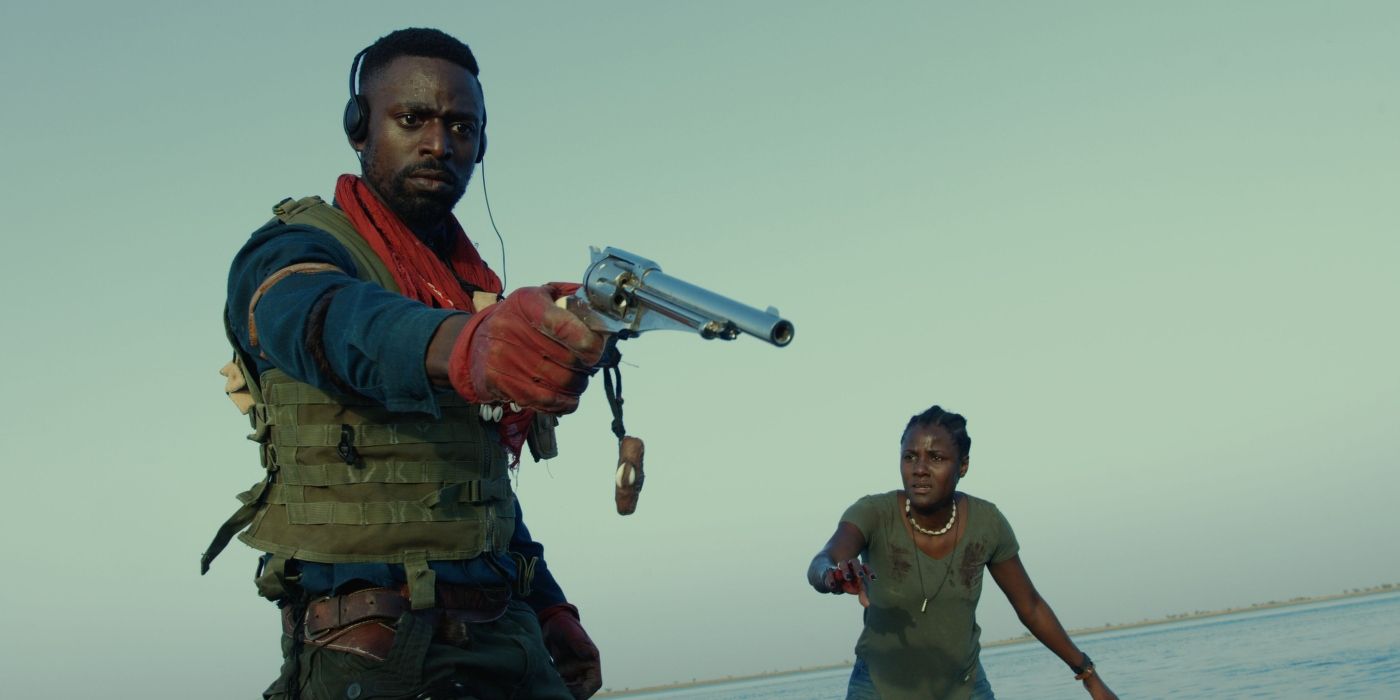 Yann-Gaël brandishing a gun on an unseen antagonist for the film Saloum (2021) 