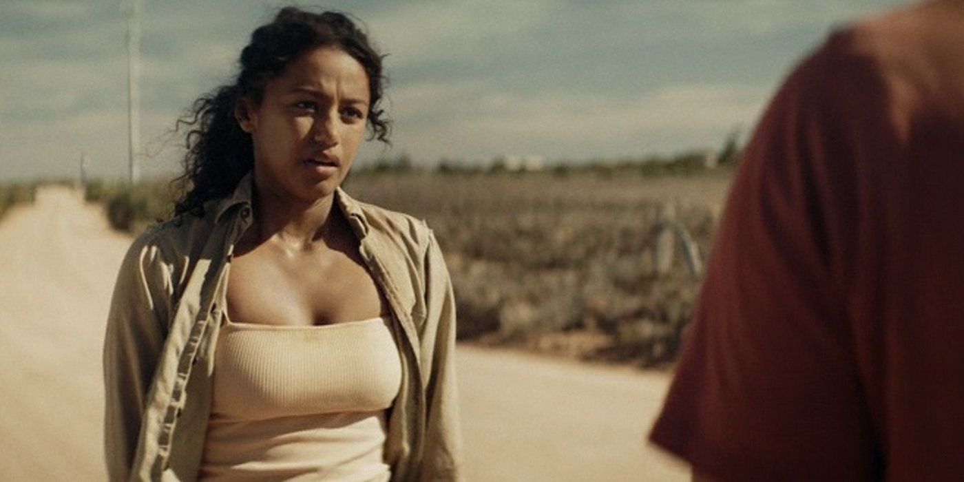 Shalom-Brune Franklin as Luci Miller standing on a dirt road talking to someone off-screen in The Tourist
