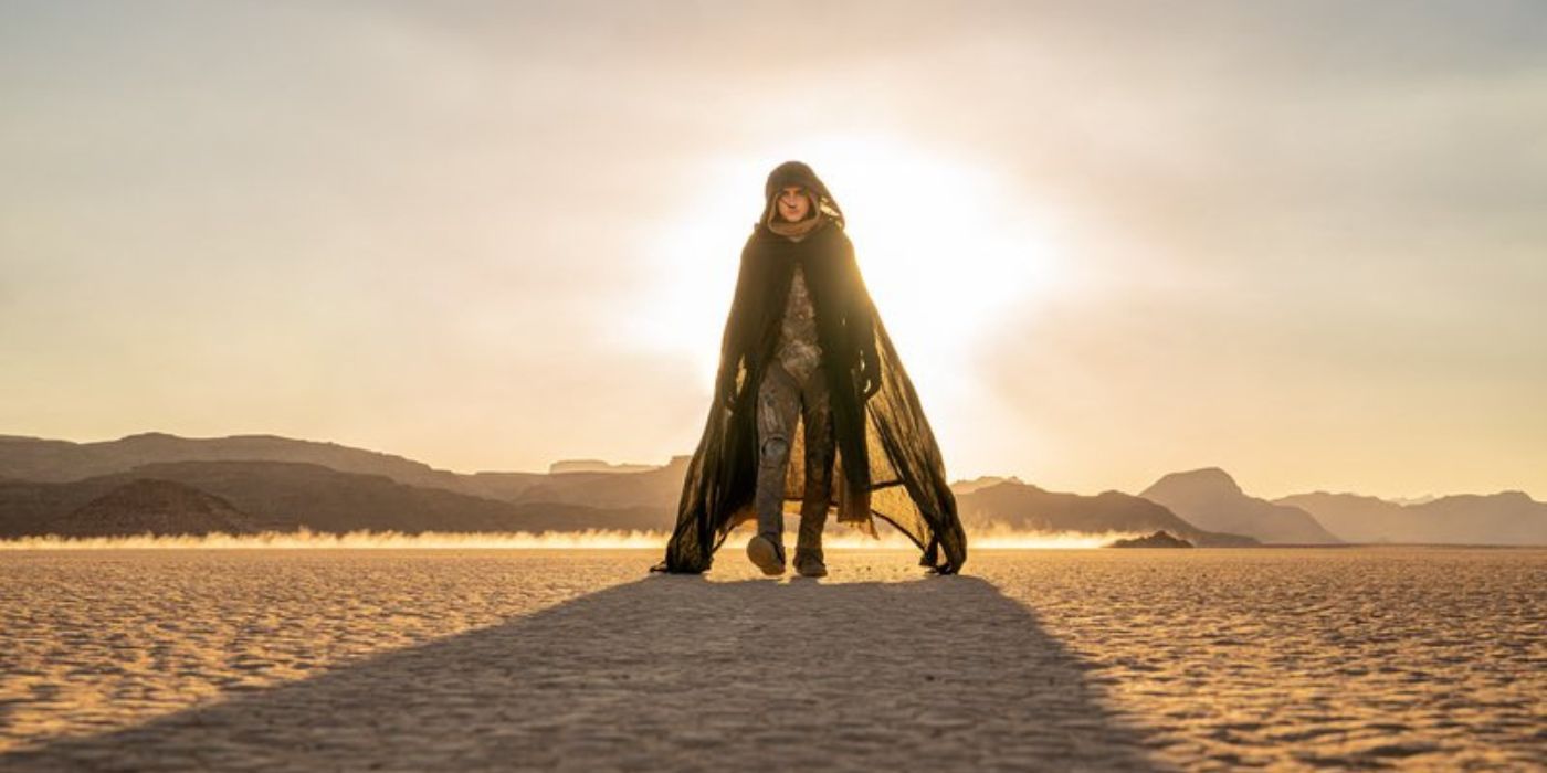 Timothée Chalamet as Paul Atreides walking through the desert while wearing a dark robe in Dune: Part Two