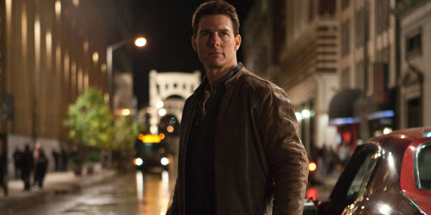 Still of Tom Cruise as Jack Reacher wearing a brown jacket next to his red muscle car from the Jack Reacher films