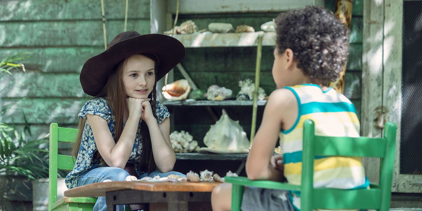 Judith sitting across from RJ playing a game on a table in The Walking Dead.