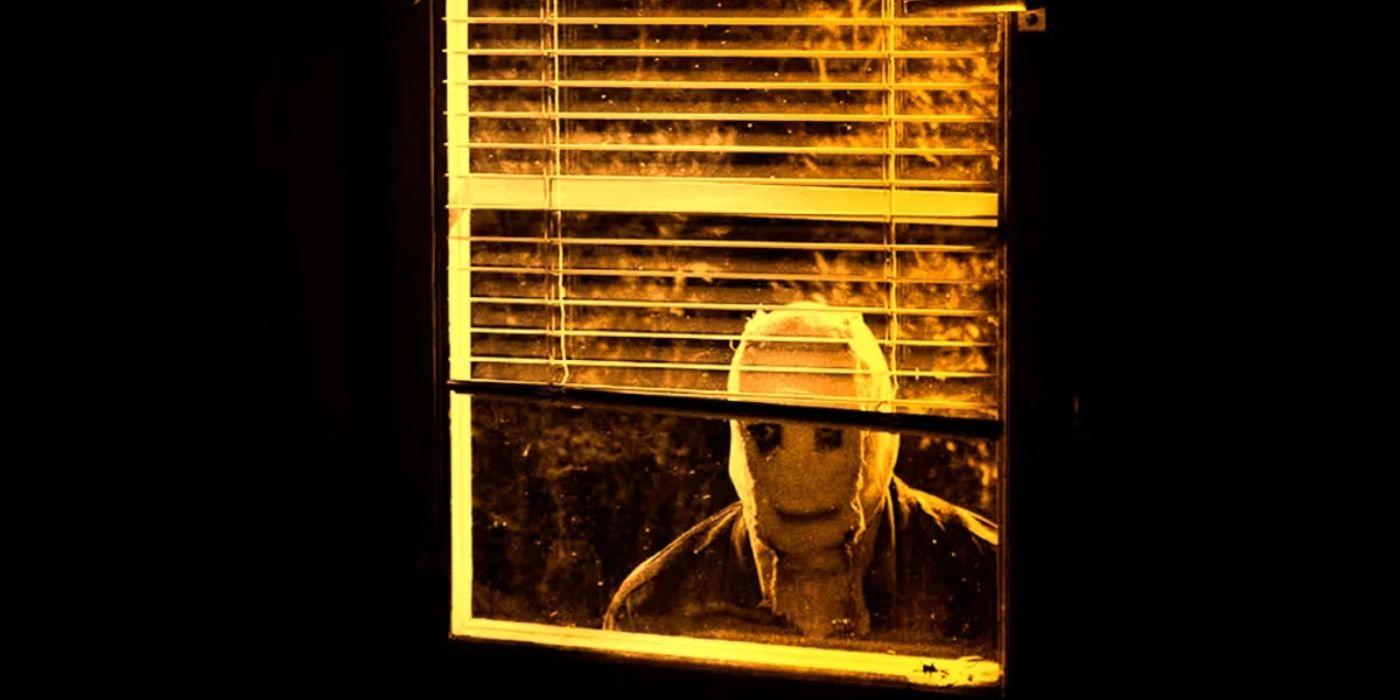A masked person in a window in The Strangers Chapter 1