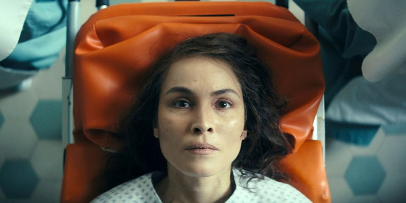 Noomi Rapace lying down in a medical room looking up toward the camera in Constellation