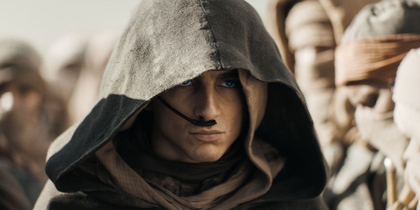 Timothee Chalamet as Paul Atreides wearing a hoodie walking through a crowd of Fremen in Dune: Part Two