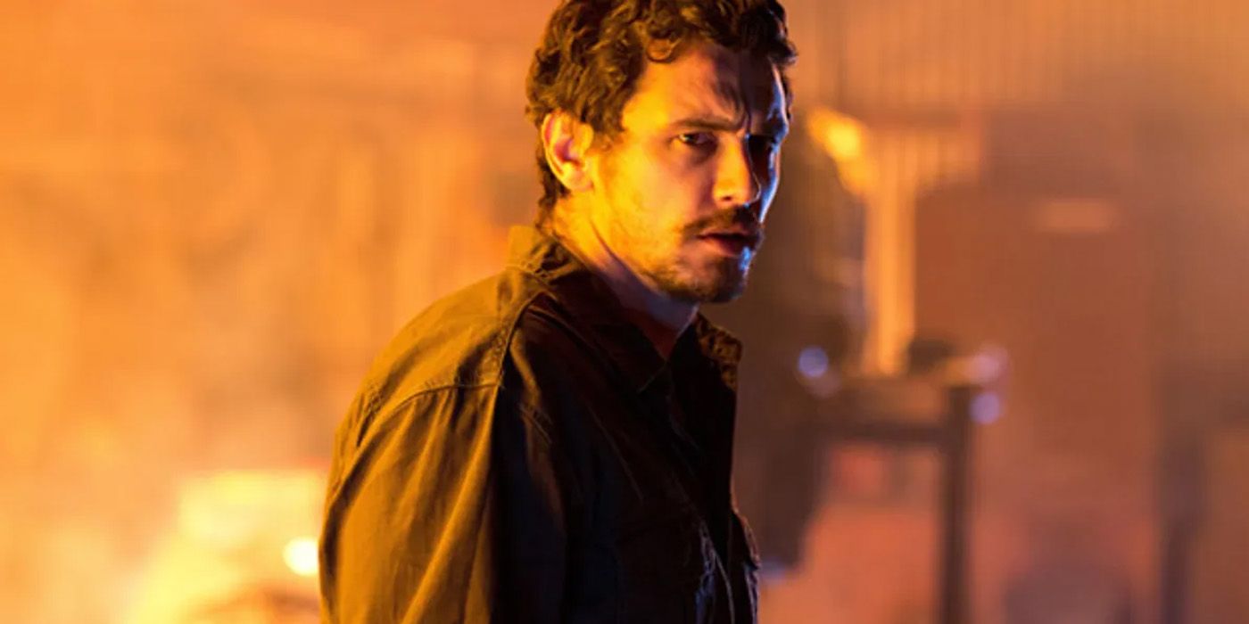 James Franco looking around at different cages with a fire raging in the background in Rise of the Planet of the Apes