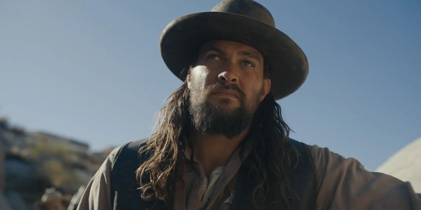 Jason Momoa in a hat leaning against an object in a desert as Big Jim in The Last Manhunt