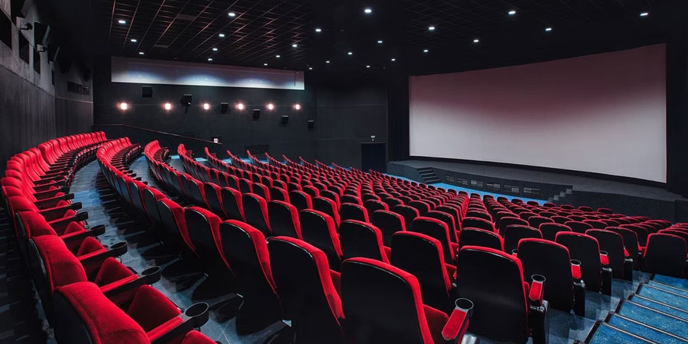 An image of empty red movie theater seats with a blank screen in the front