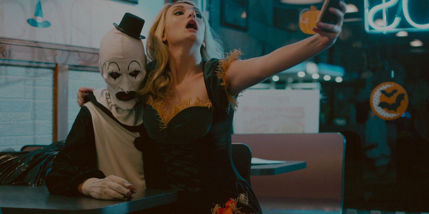 David Howard Thornton as Art the Clown in Terrifier with a girl sitting on his lap taking a selfie