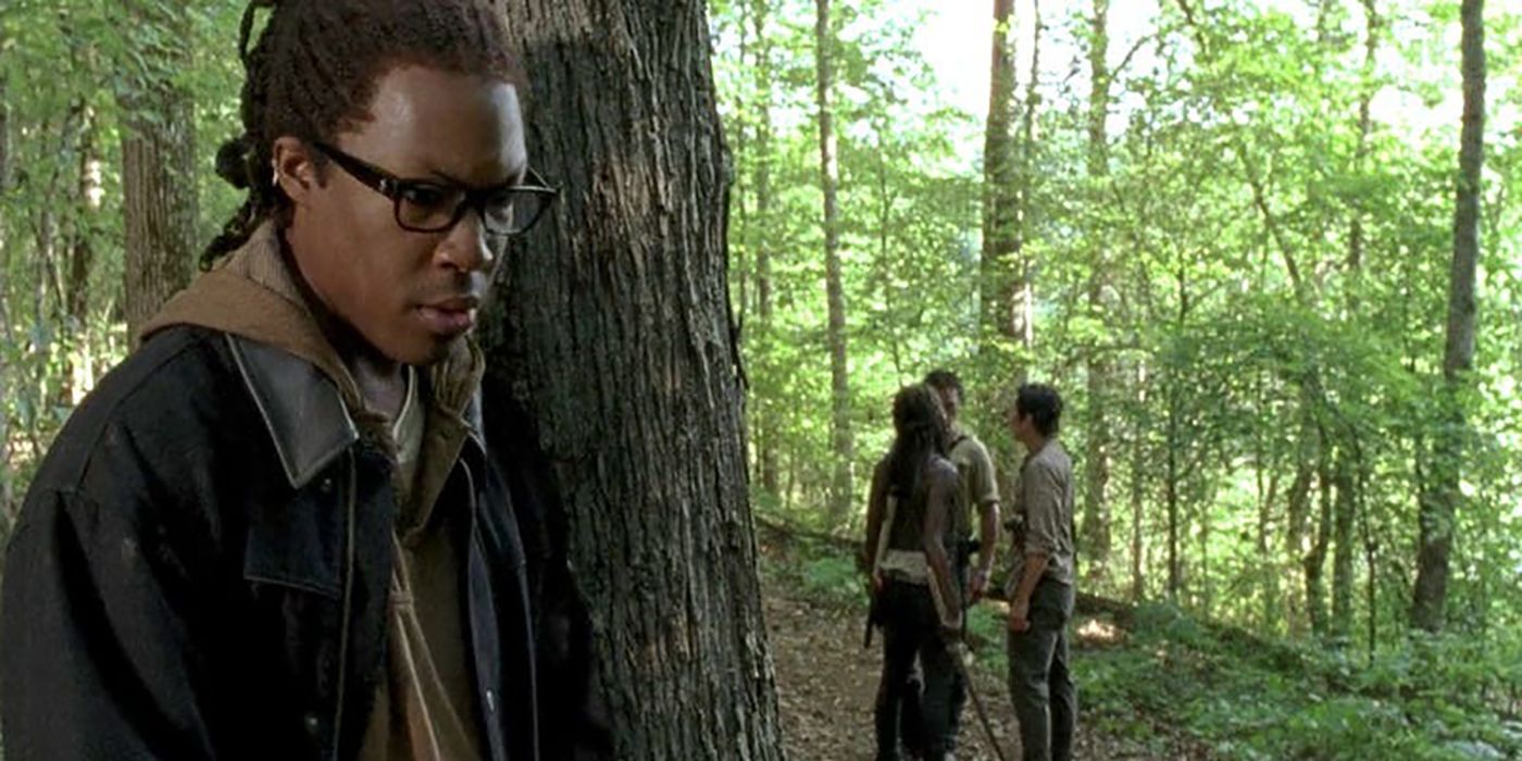 Heath hiding behind a tree in the forest listening to plans on The Walking Dead