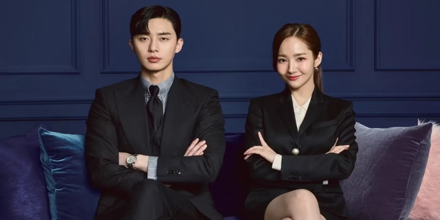 Park Seo-joon as Lee Young-joon and Park Min-young as Kim Mi-so sit on a sofa in dark suits for the poster for What's Wrong with Secretary Kim?