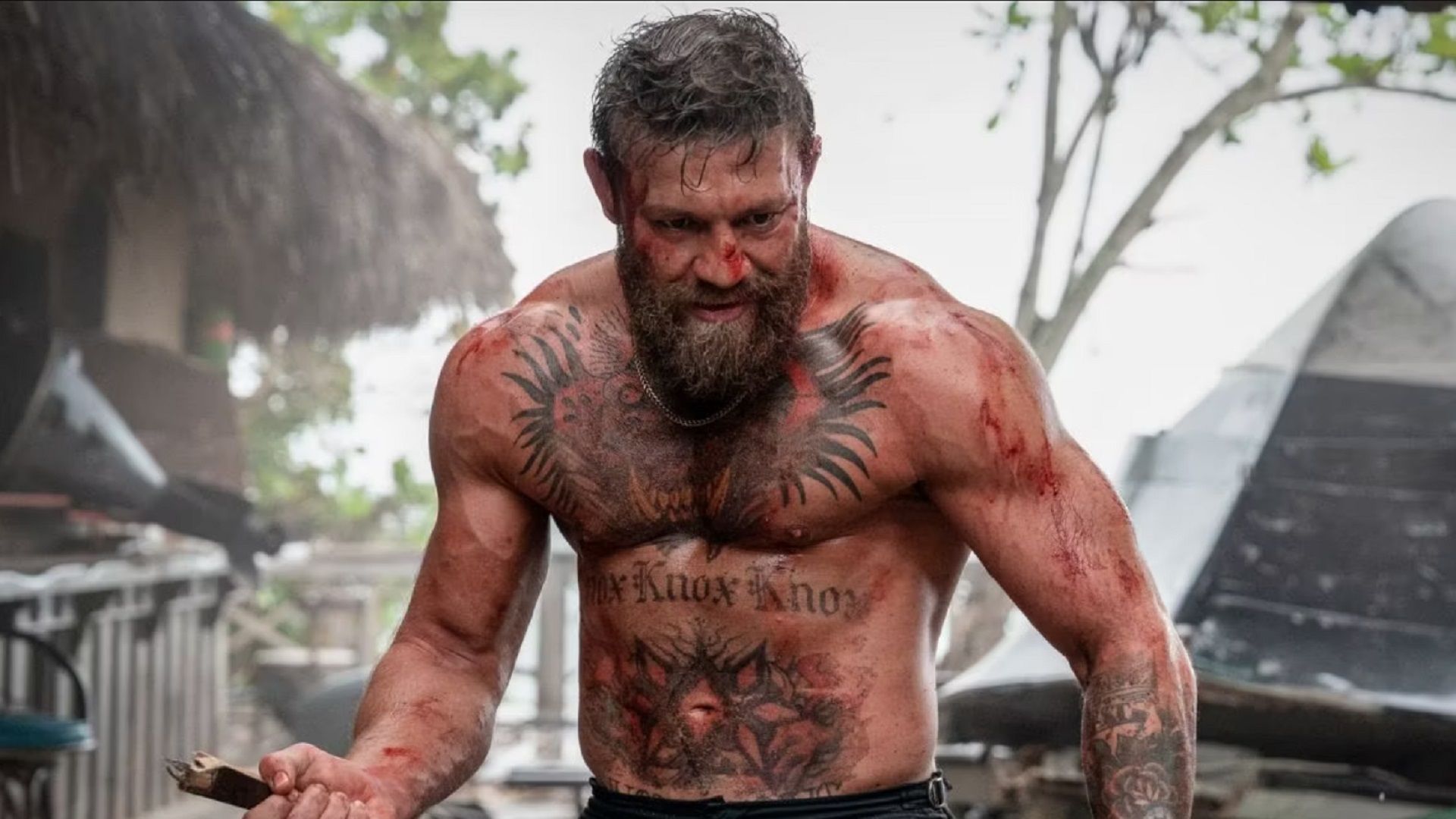 Conor McGregor holding a knife with blood on his arms and chest in Road House