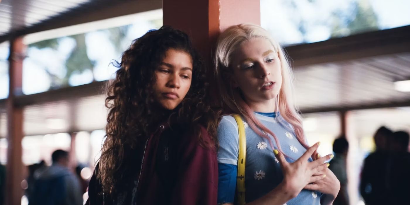 Zendaya and Hunter Schafer leaning against a pole outside their high school in Euphoria