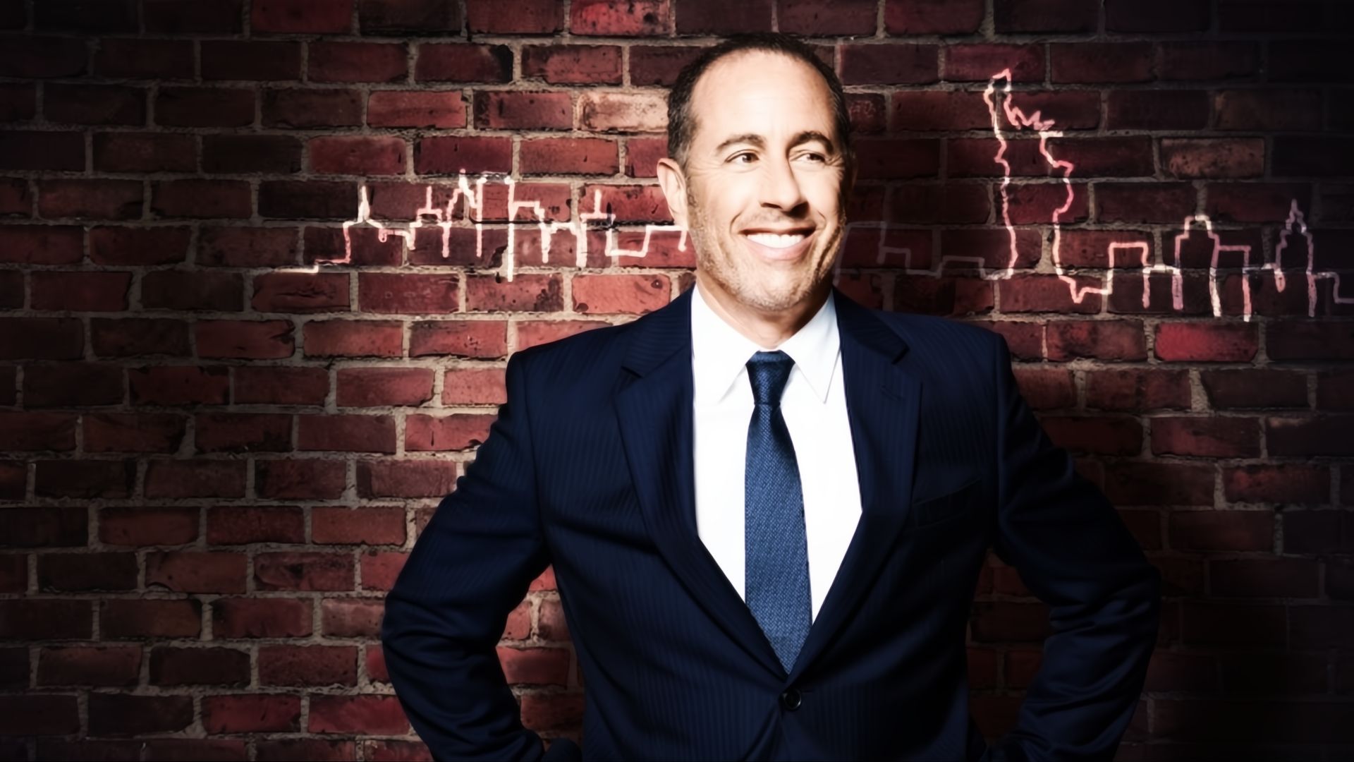 Jerry Seinfeld in a suit by a brick wall in Jerry Before Seinfeld