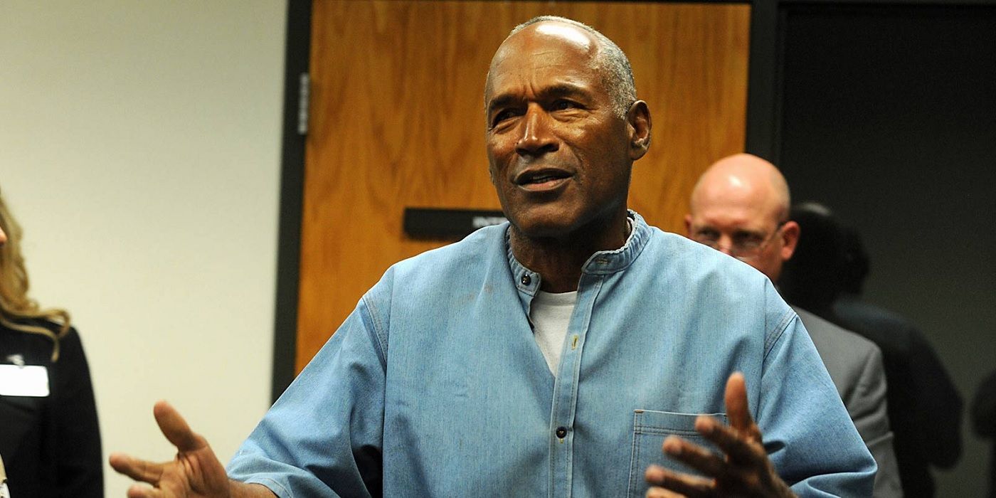 O J Simpson with arms outstretched wearing a blue shirt