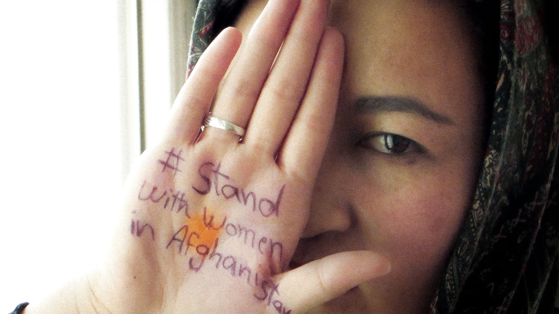 Stand with Women in Afghanistan written on the hand of a woman in the movie Bread and Roses