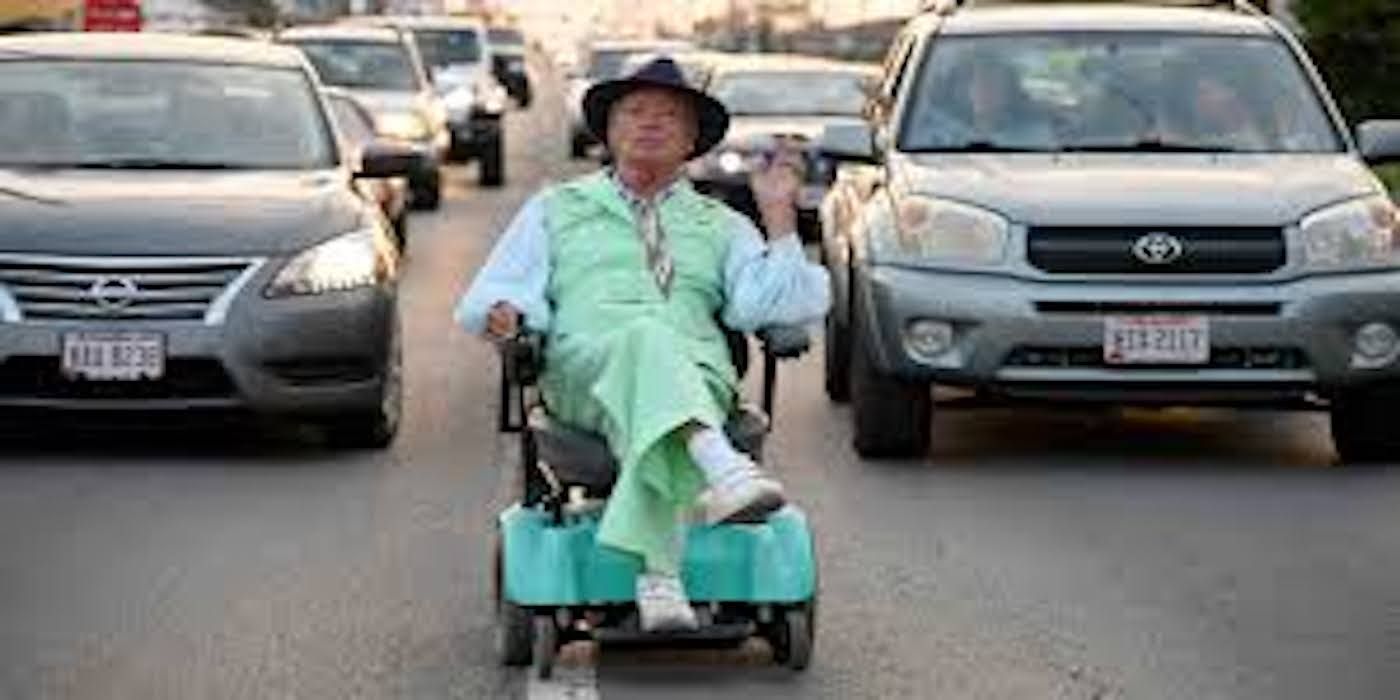 A man sits in a wheelchair in the road in Swan Song