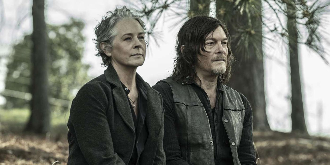 Carol and Daryl sitting together in the forest, looking ahead and smiling slightly on The Walking Dead.