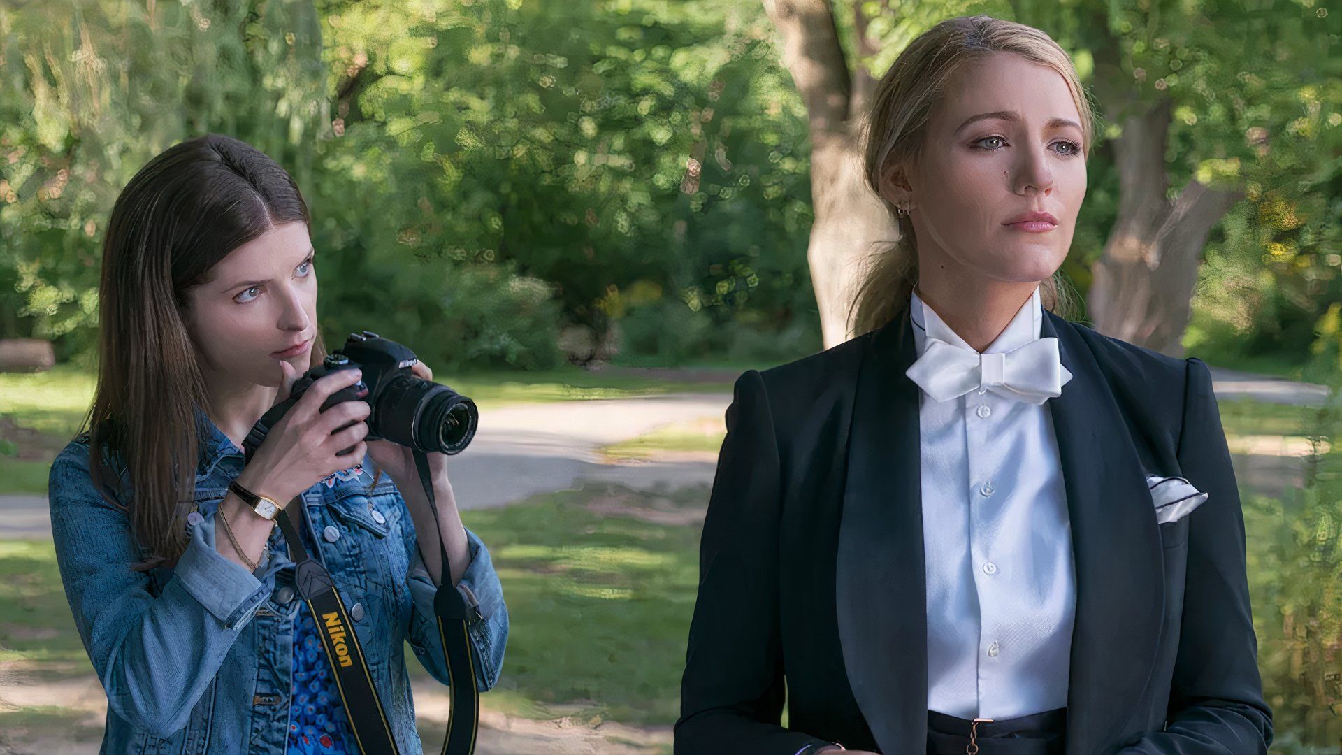 Anna Kendrick and Blake Lively in A Simple Favor with Kendrick taking a photo in a park